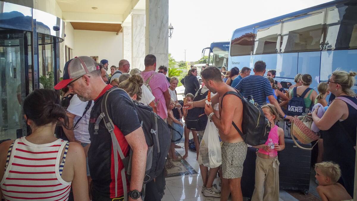 Evacuees wait to board on buses as they leave their hotel during a forest fire on the island of Rhodes, Greece on July 23. Picture by Argyris Mantikos/Eurokinissi via AP